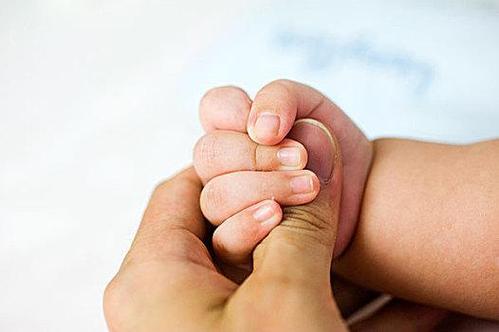 家长给新生儿掰手指练抓握的实拍