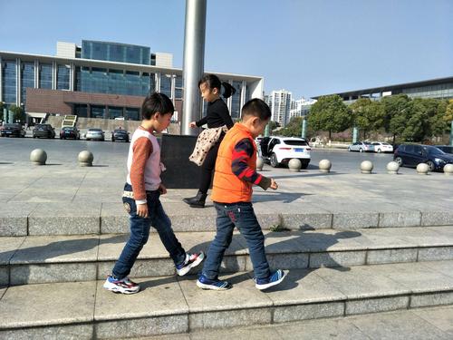 小学家长带孩子在小区步道上测量步行速度的亲子实景图