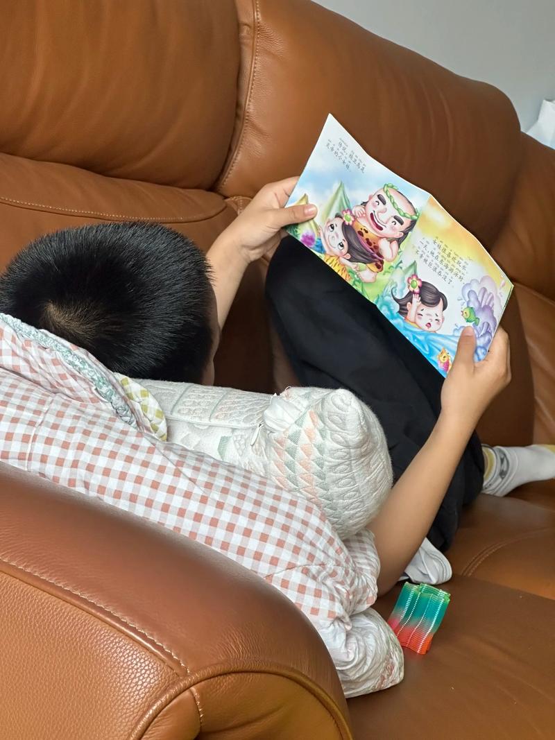小朋友趴在沙发上翻绘本的居家实拍
