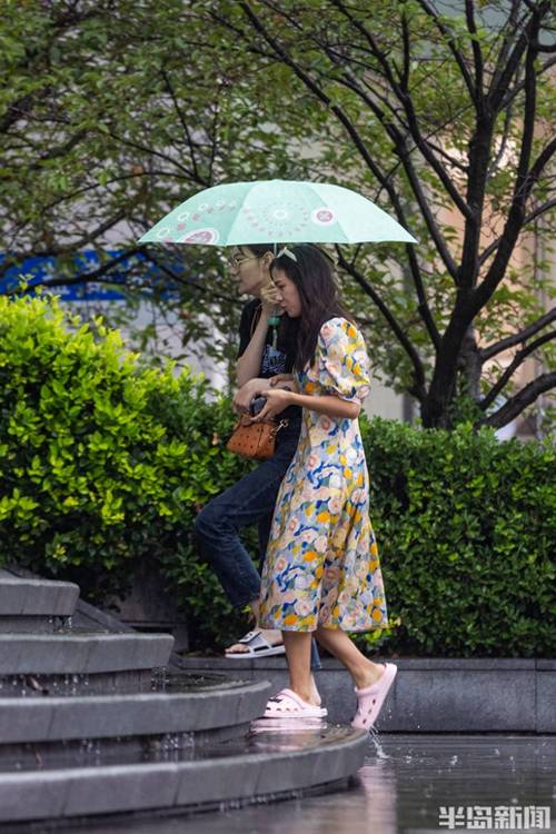 梅雨季街边撑伞打湿裤脚的行人
