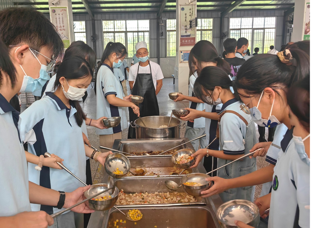 中学校长课间在食堂帮学生整理餐盘的实拍图