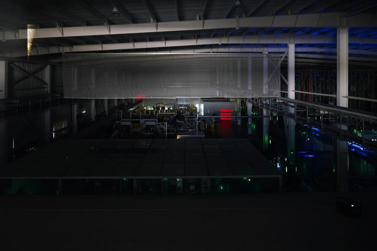 工业机器人停机后臂杆自然垂落的车间夜景