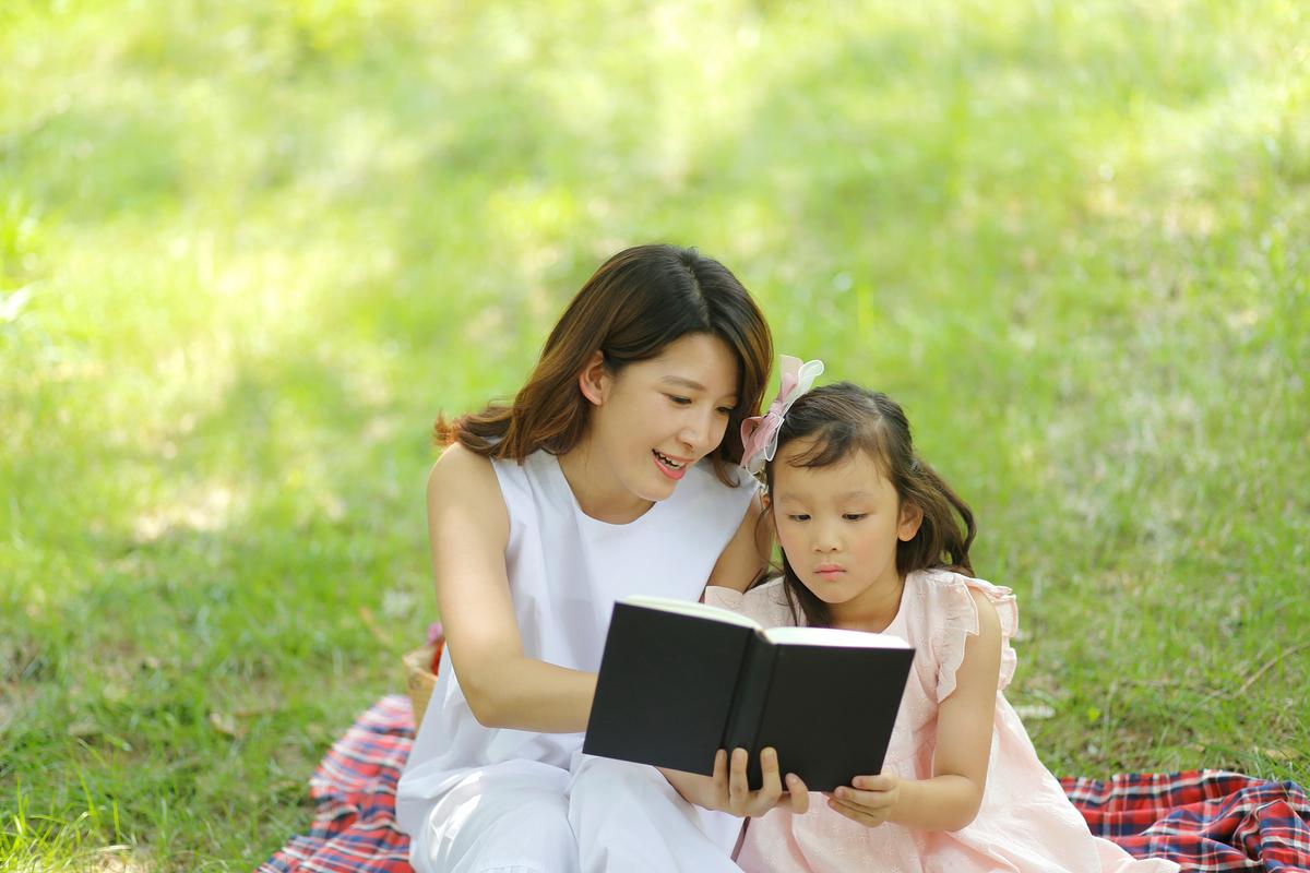 妈妈陪孩子草地上看书松弛感育儿日常场景