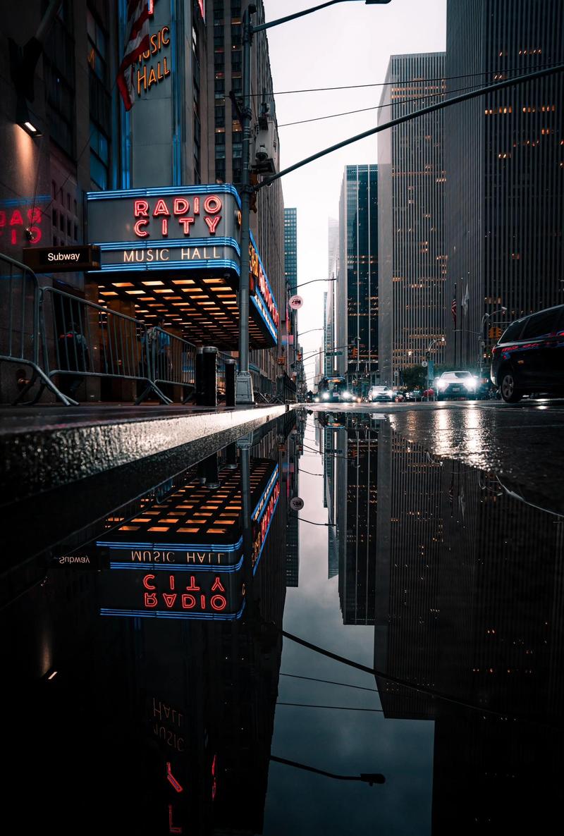 雨夜城市街道霓虹灯倒影中摄影师抓拍匆匆行人