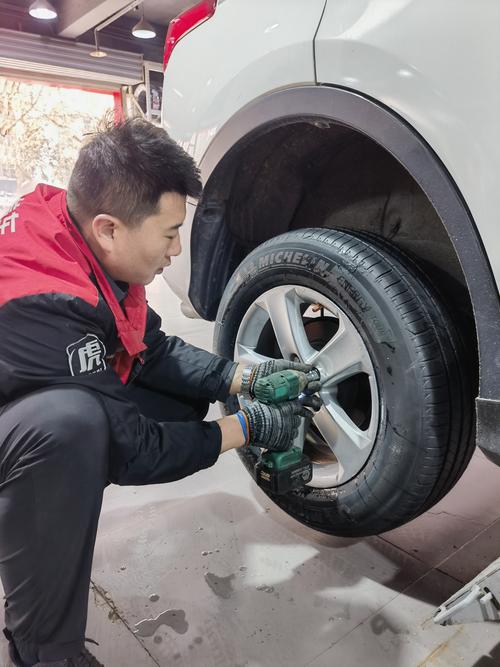 南京汽修店师傅蹲在车边用手掌摸轮胎内侧胎面