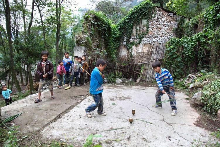 孩子们在水泥地上玩木质陀螺
