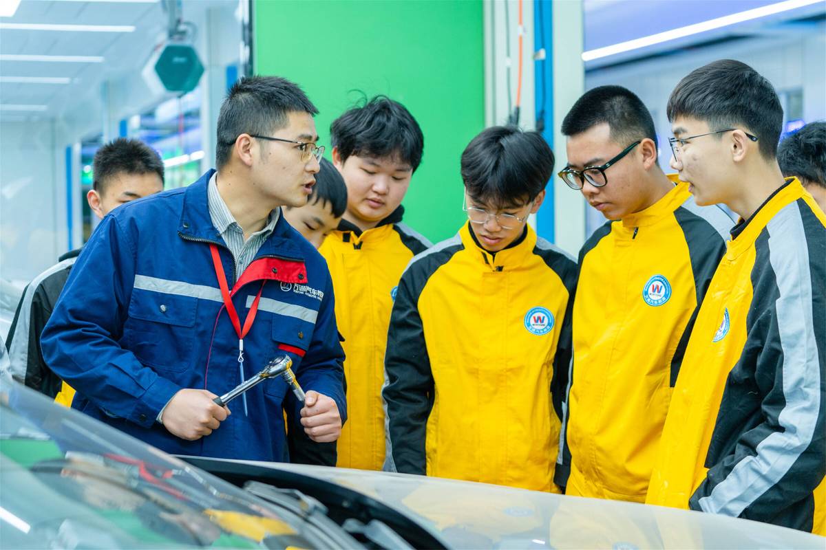 现代学徒制学生与师傅在新能源汽车维修车间