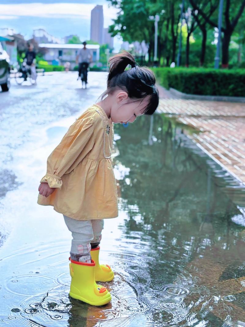 雨后孩童穿着雨鞋踩水坑妈妈不远不近守望场景