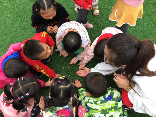 小学科学课老师带学生操场观察蜗牛爬痕场景