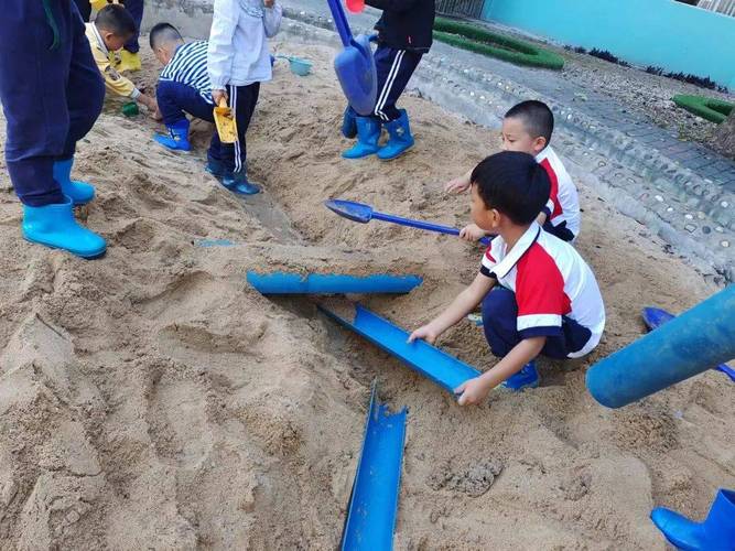 幼儿园孩子沙坑里合作搭建水渠游戏场景