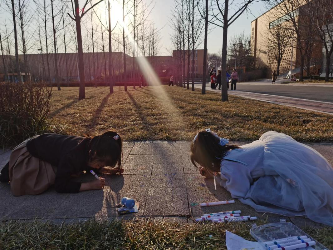 两个孩子在地板上专注画画,大人静坐一旁