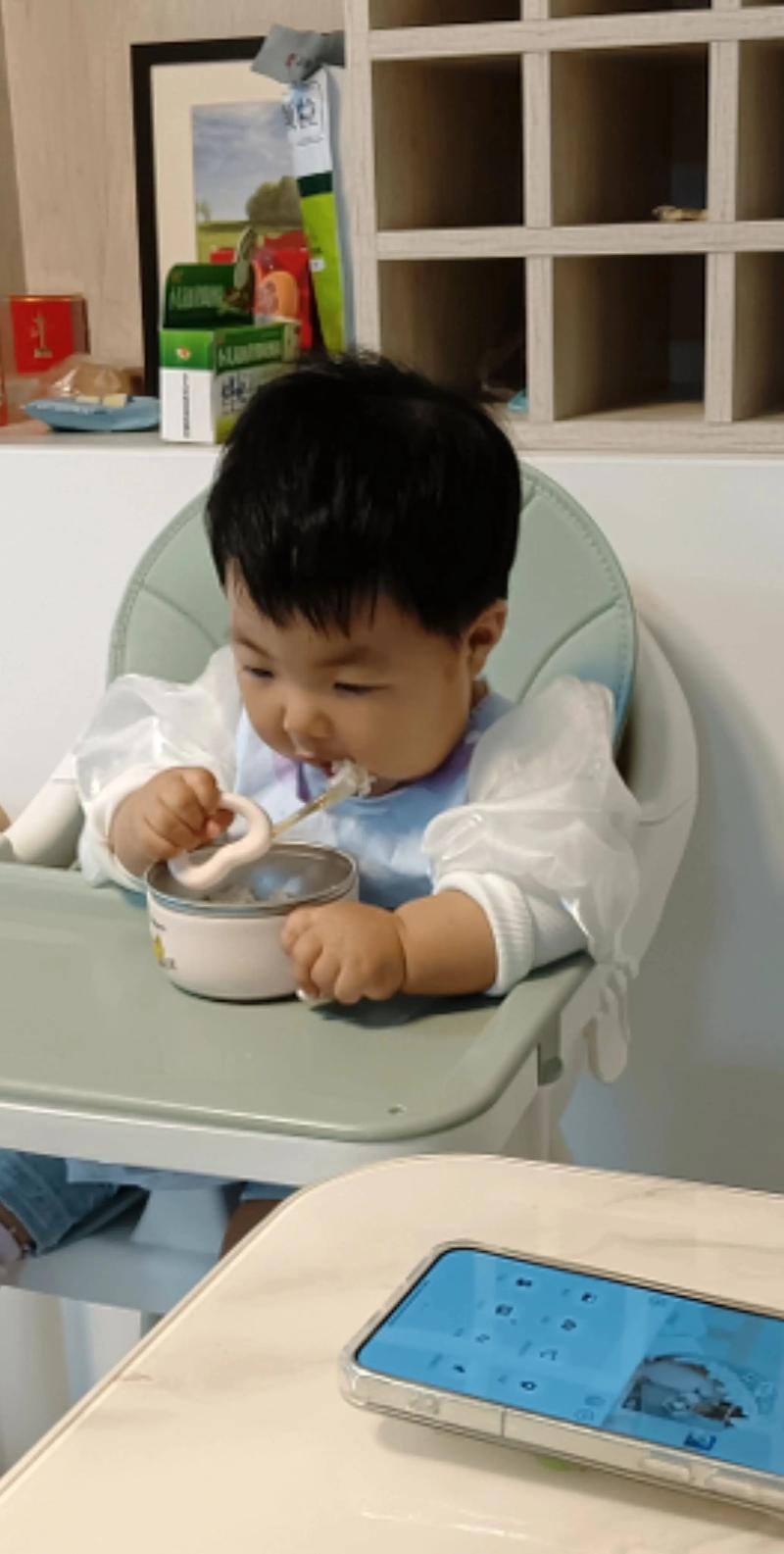 幼儿自己拿勺子吃饭的实拍图
