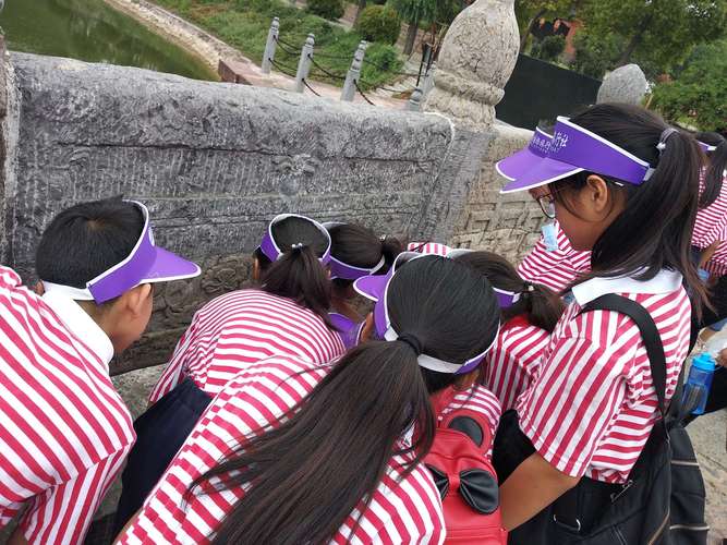 小学老师带领学生在户外观察石桥