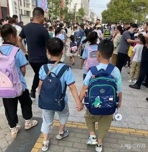 小学低年级学生放学被家长拽着胳膊说话的校门口场景