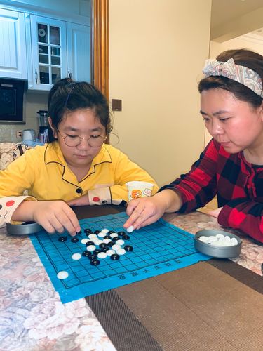 家长和小孩趴在餐桌上下跳棋的温馨日常