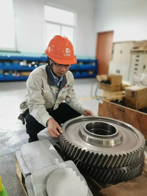 车间工人蹲在铣床旁检查报废齿轮工件