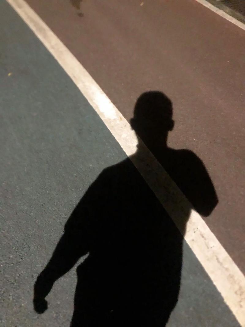 一个人在夜晚路灯下跑步的剪影远处城市灯光