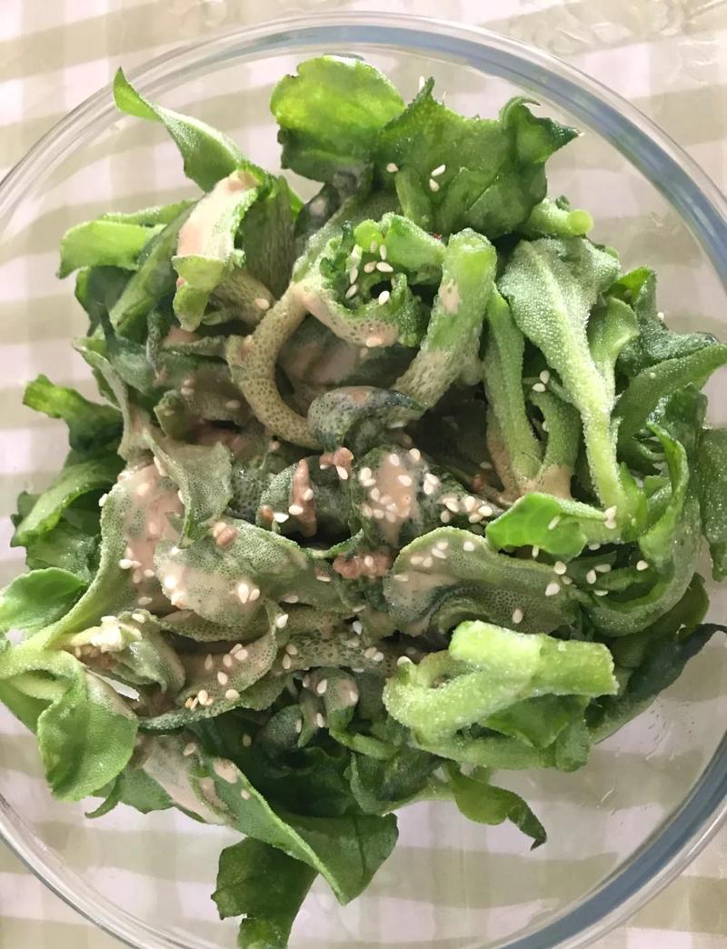 玻璃碗中调配凉拌菜料汁加熟芝麻的实拍图