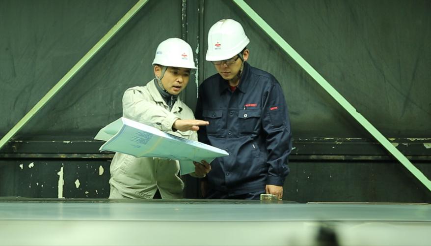 钢铁厂车间主任与工人在操作台前交流