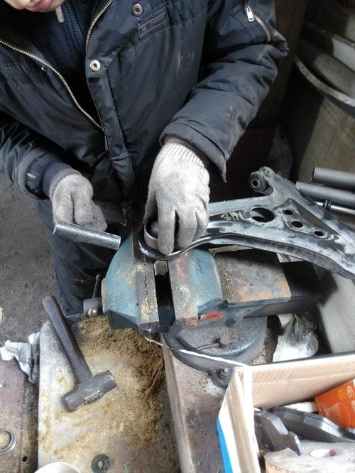 汽修师傅用撬棍撬动下摆臂检查胶套间隙