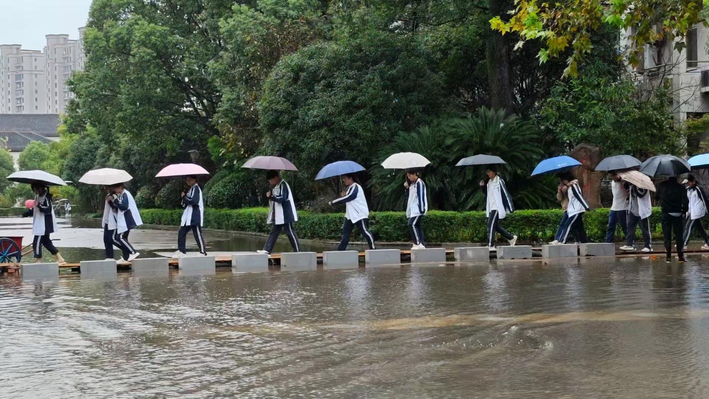 中学教学楼暴雨后男生蹲在门口帮同学拖鞋底积水的场景