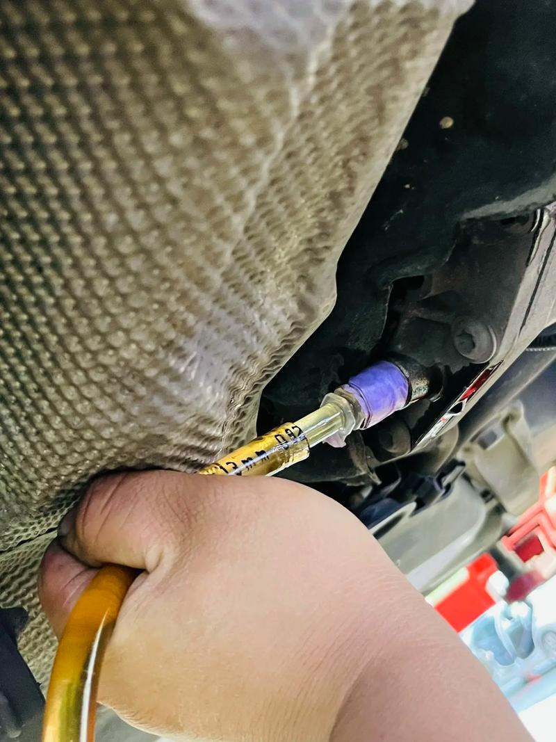 汽修师傅用注射器抽取差速器旧齿轮油检查状态