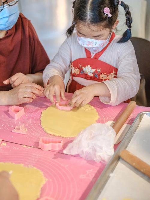 社区活动中心亲子烘焙活动 小朋友沾着奶油的手按饼干模具