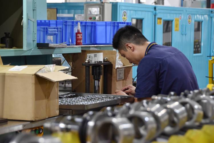 工业车间门口工人帮新员工整理碰倒的工件