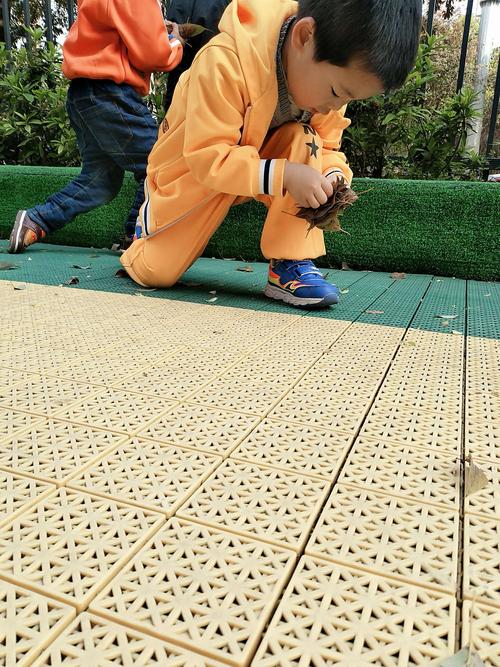 3岁幼儿蹲在小区台阶上数地砖的实拍图