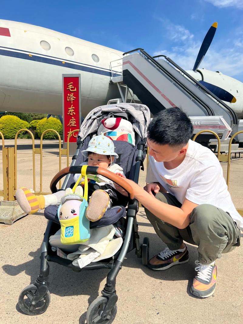 工业车间里男性全职爸爸背着婴儿带娃操作机床
