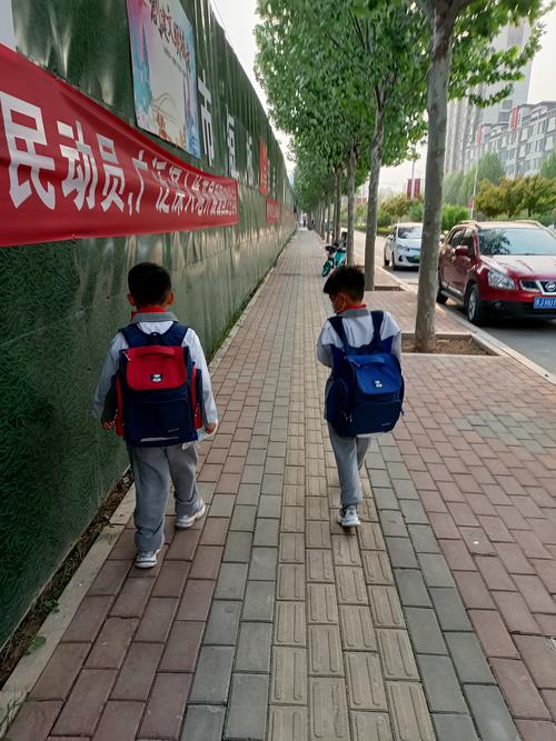 当代工业区家属院小学生结伴走路上学哼歌图