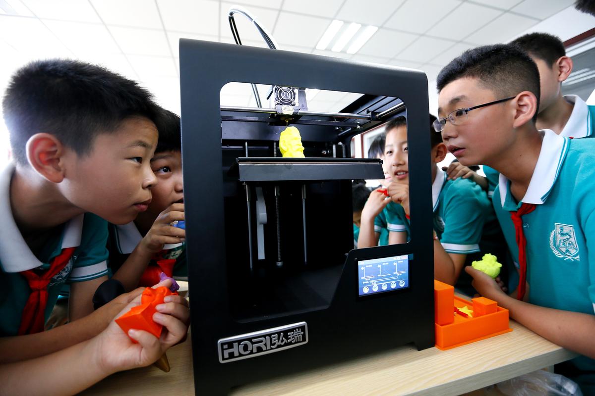 教师指导儿童操作桌面级3D打印机
