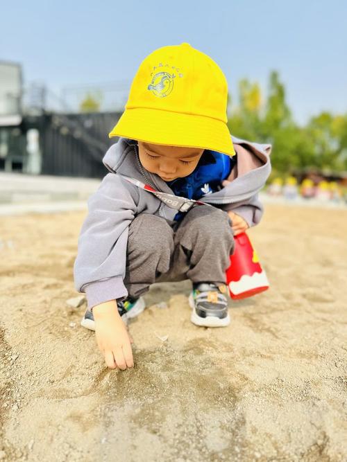 幼儿园孩子独自蹲在沙坑边背影照