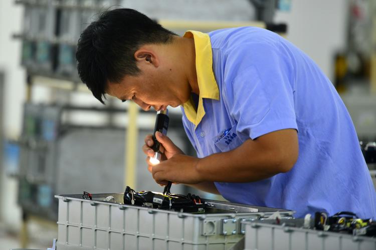 工匠父亲在车间指导儿子检查产品质量的特写