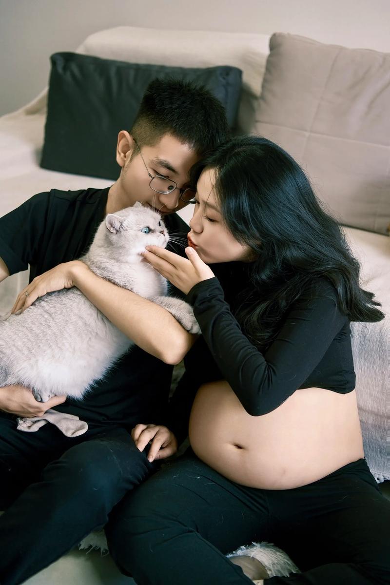 孕晚期准妈妈和家中橘猫同坐沙发照片