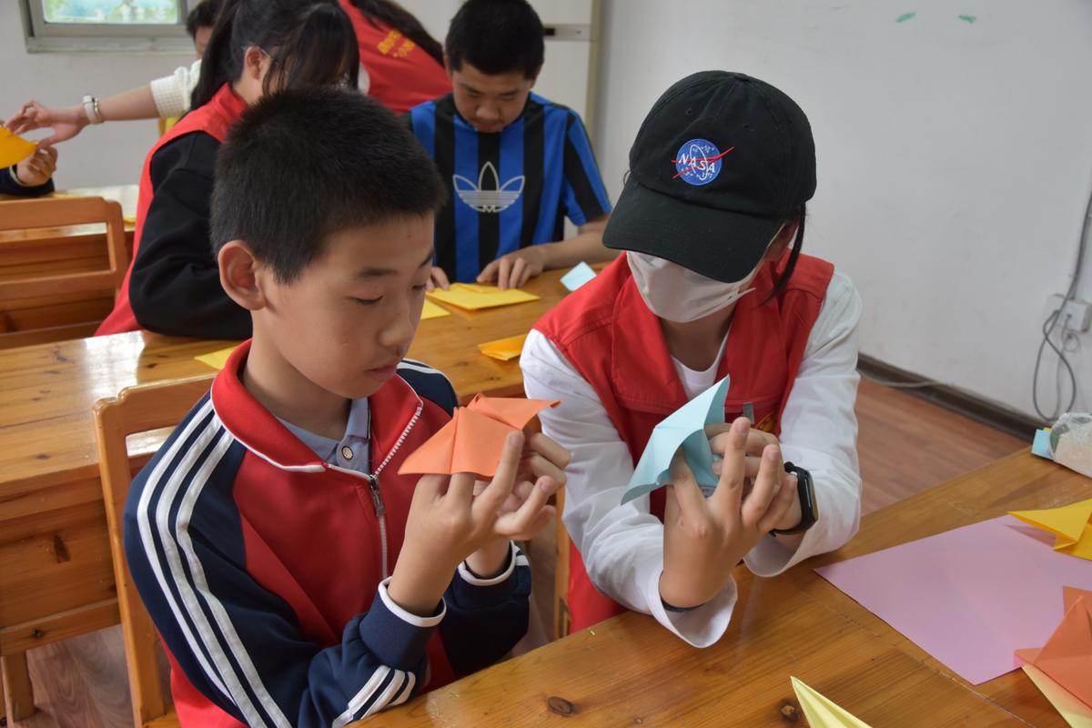 小学生合作帮助脑瘫同学做手工