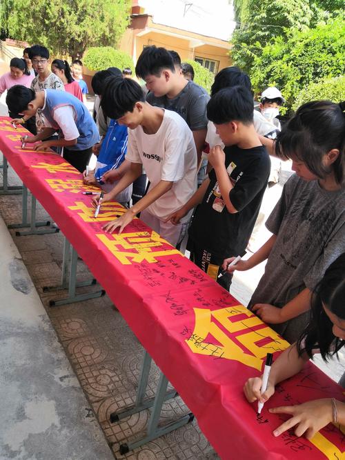 中学走廊里学生对着生命教育宣传单签字的场景