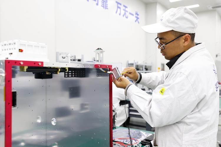 科研人员在工厂车间调试设备 汗流浃背