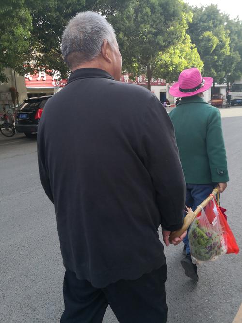 菜市场白发老夫妻牵手买菜背影