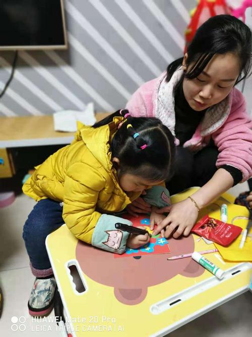 妈妈和4岁女儿坐在地毯上用蜡笔在小卡片上画事件拆拆卡的实拍图