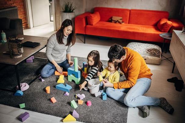 4岁幼儿蹲在地板上用塑料玩具搭想象场景的实拍图