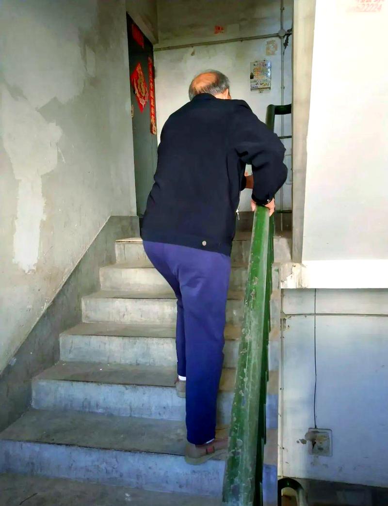 老旧小区楼道内老人扶墙走路锻炼照片