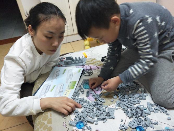 家长蹲在地上和孩子一起拼装机械零件的实拍图