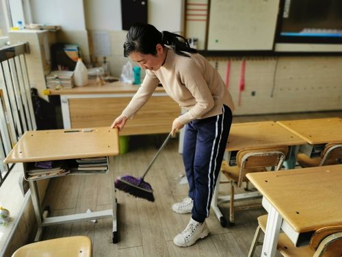 老教师蹲在教室地板缝边清扫粉笔头的背影