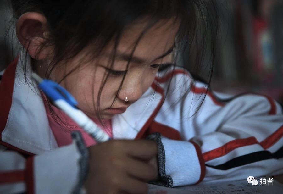 穿校服的小学生咬着铅笔头站在书桌边掉眼泪