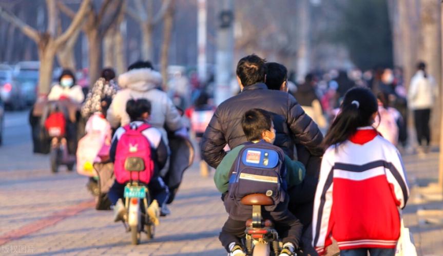 工业园区年轻爸爸接孩子放学路边等车的实拍图
