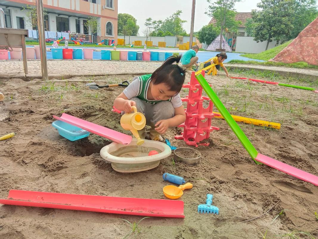 幼儿园孩子户外玩沙池活动场景