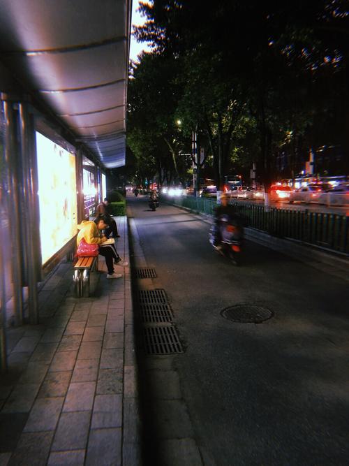 城乡公交站台台阶上写作业的女孩