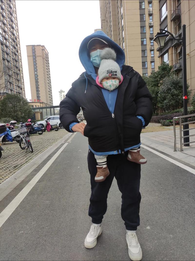 家长给儿童穿过多厚衣服的冬季日常场景