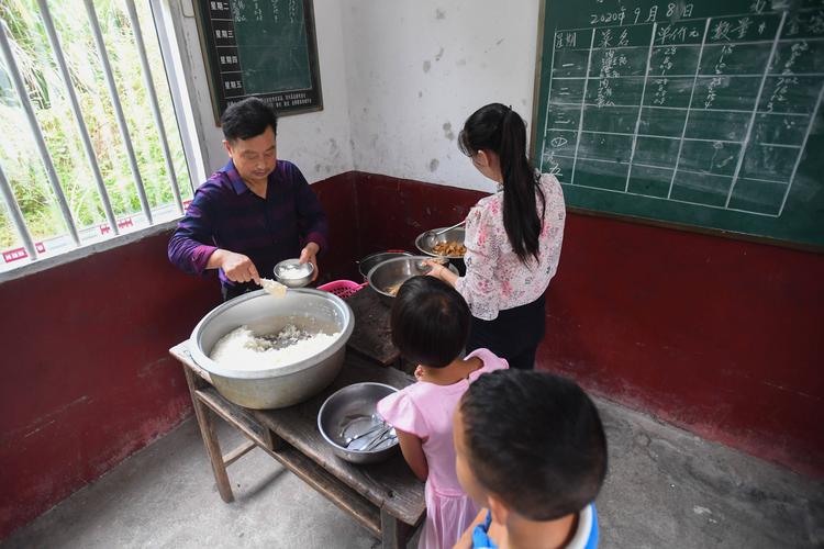 乡村教师课间在灶台边给学生热午饭的场景